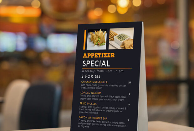 Mock up Label the blank menu frame in Bar restaurant ,Stand for booklets with white sheets paper acrylic tent card on wooden table cafeteria blurred background can inserting the text of the customer.