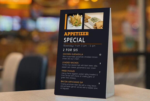 Mock up Label the blank menu frame in Bar restaurant ,Stand for booklets with white sheets paper acrylic tent card on wooden table cafeteria blurred background can inserting the text of the customer.